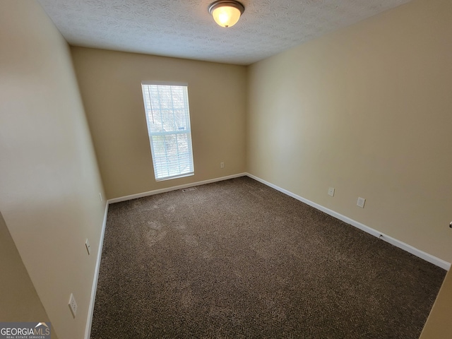 unfurnished room with dark carpet, a textured ceiling, and baseboards