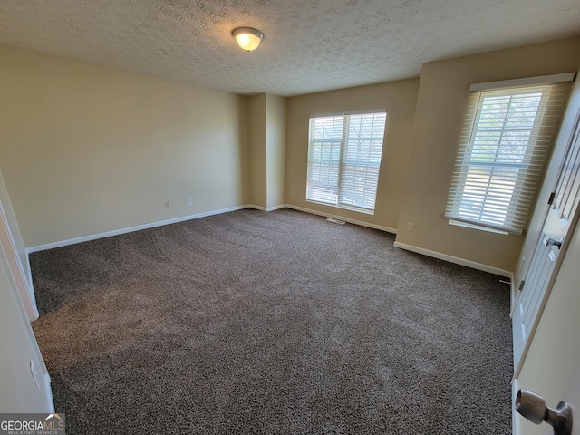 empty room with baseboards, dark carpet, and a textured ceiling