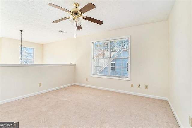 carpeted empty room featuring visible vents, ceiling fan, a textured ceiling, and baseboards