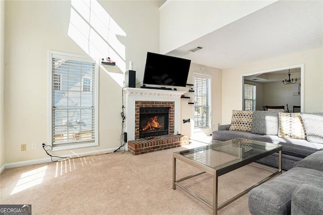 living room with carpet, a notable chandelier, a fireplace, visible vents, and baseboards