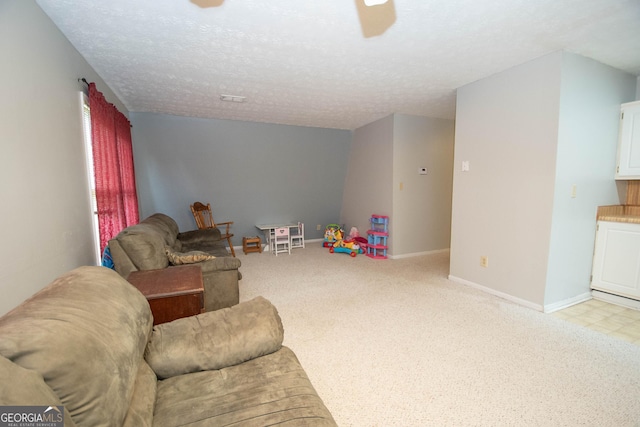 rec room with a textured ceiling, light carpet, a ceiling fan, and baseboards