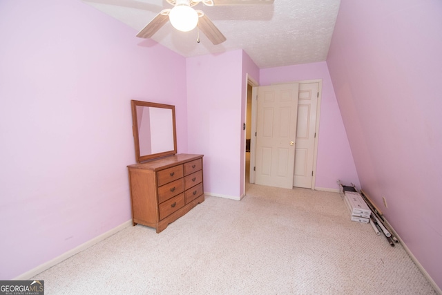 unfurnished bedroom featuring light carpet, ceiling fan, baseboards, and a textured ceiling