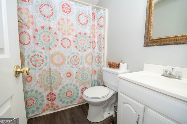 bathroom featuring toilet, a shower with shower curtain, wood finished floors, and vanity