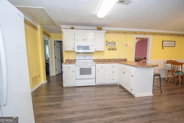 kitchen featuring white appliances, visible vents, a peninsula, a textured ceiling, and white cabinetry