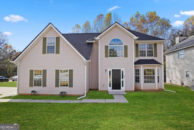 view of front of home with roof with shingles and a front yard