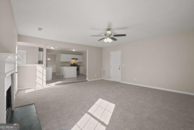 unfurnished living room featuring a fireplace with flush hearth, light colored carpet, visible vents, and baseboards