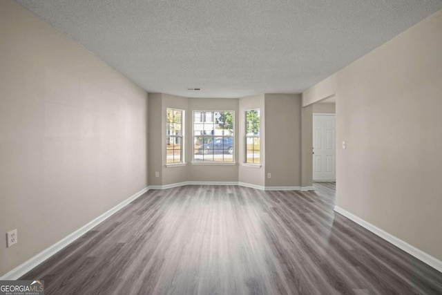 unfurnished living room with visible vents, baseboards, dark wood finished floors, and a textured ceiling