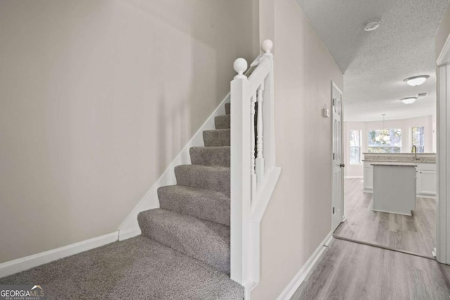 stairs with a textured ceiling, baseboards, and wood finished floors