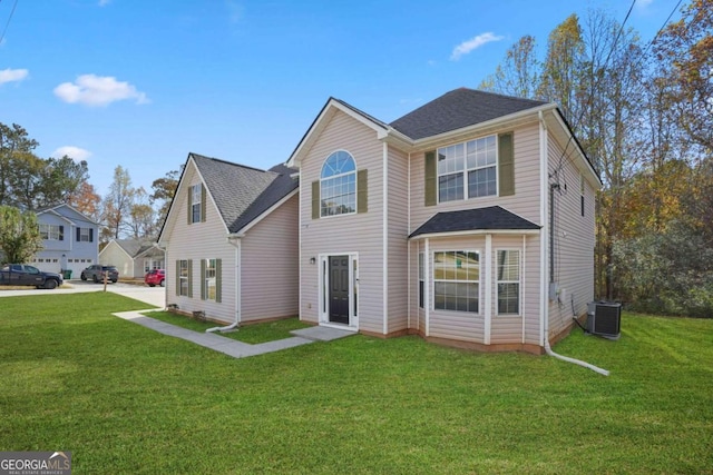 traditional home featuring a front yard, roof with shingles, and central AC unit