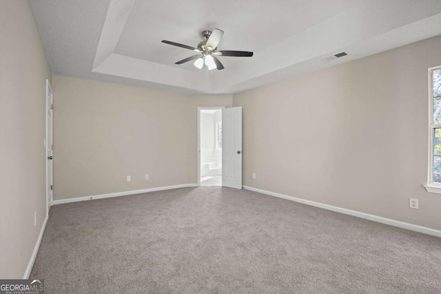 empty room with baseboards, carpet, visible vents, and a tray ceiling