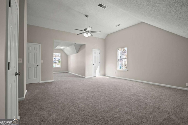 additional living space featuring lofted ceiling, visible vents, ceiling fan, a textured ceiling, and baseboards