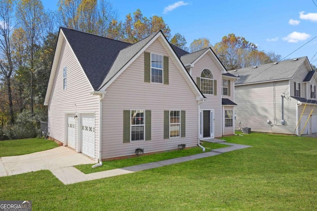 traditional-style home with an attached garage, driveway, a shingled roof, and a front yard