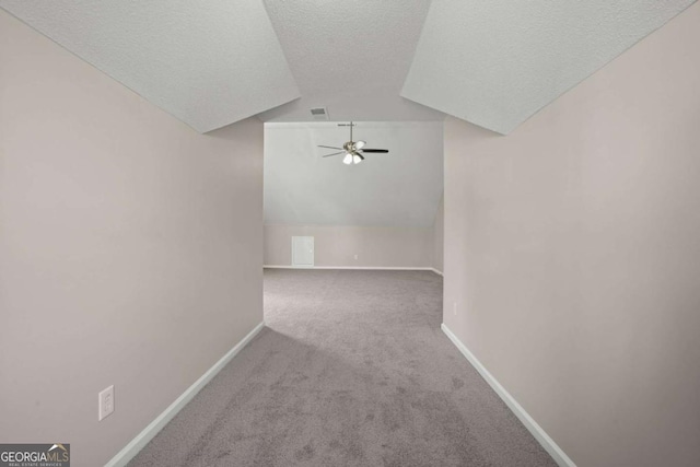 bonus room featuring lofted ceiling, carpet, a textured ceiling, and baseboards