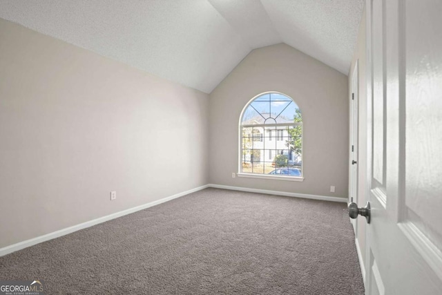 carpeted empty room with lofted ceiling, a textured ceiling, and baseboards