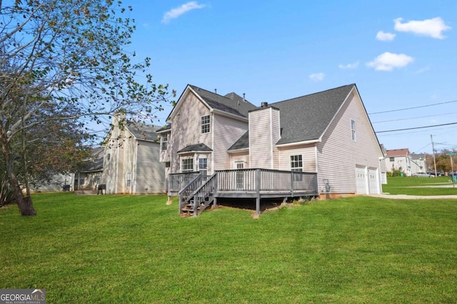 back of house with a garage, driveway, a lawn, a chimney, and a deck