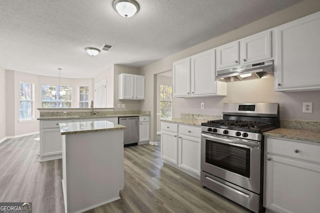 kitchen featuring visible vents, appliances with stainless steel finishes, white cabinets, a peninsula, and under cabinet range hood