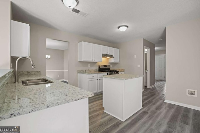 kitchen with stainless steel gas range oven, a sink, visible vents, white cabinetry, and dark wood-style floors