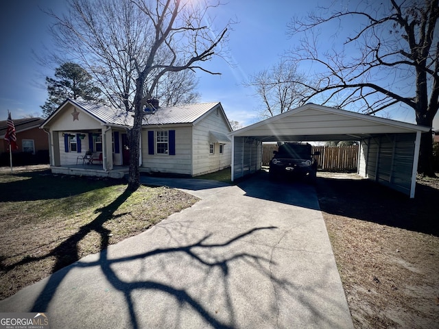 view of front of property with concrete driveway, metal roof, fence, a porch, and a carport