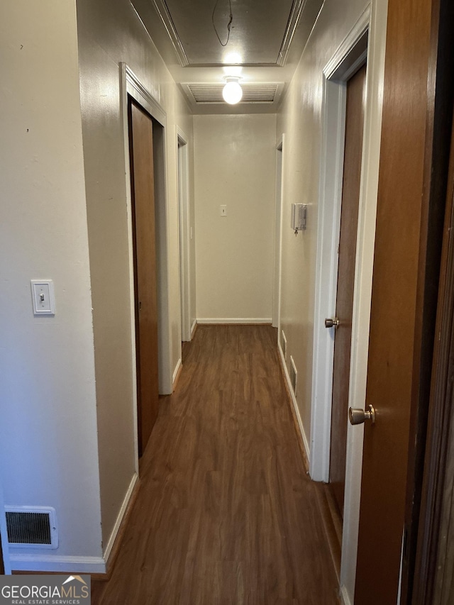 corridor with baseboards, visible vents, and wood finished floors