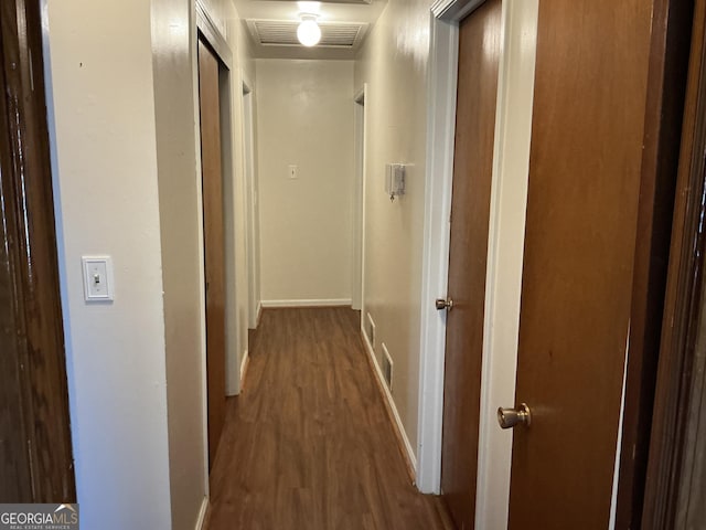 hall featuring visible vents, baseboards, and wood finished floors