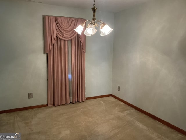 spare room featuring light colored carpet, a notable chandelier, and baseboards