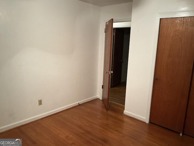 unfurnished bedroom with a closet, baseboards, and wood finished floors