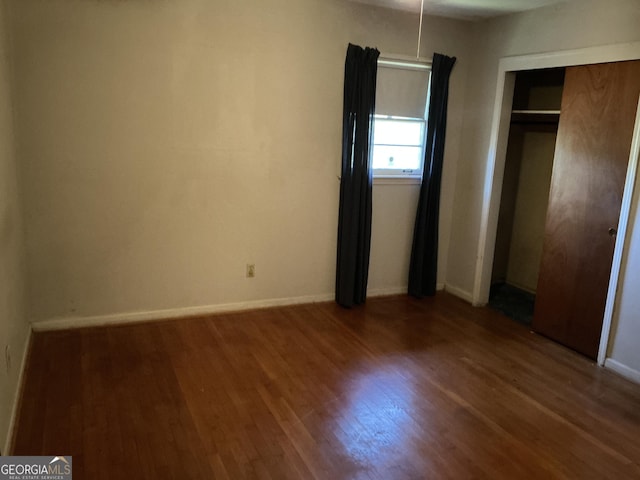 unfurnished bedroom with a closet, baseboards, and wood finished floors