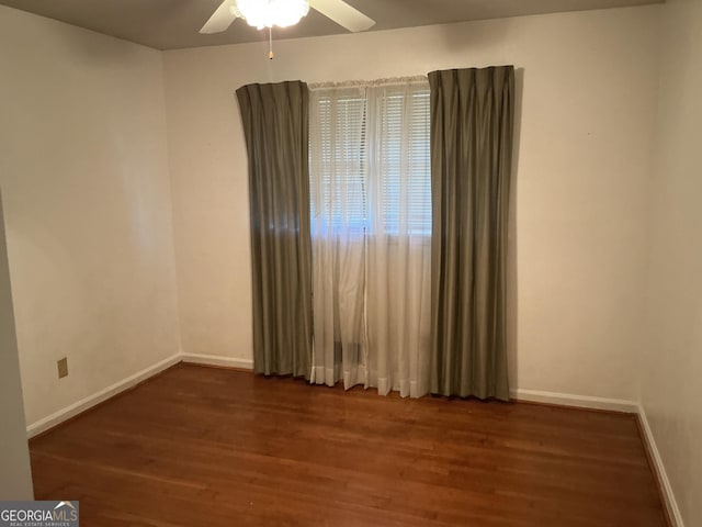 spare room featuring wood finished floors, a ceiling fan, and baseboards