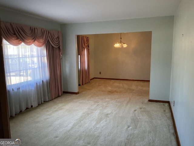 spare room featuring light carpet, a notable chandelier, and baseboards