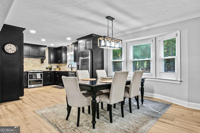 dining room featuring crown molding, a textured ceiling, baseboards, and light wood-style floors