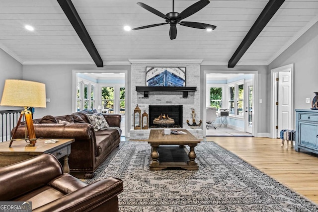 living area featuring lofted ceiling with beams, ornamental molding, wood finished floors, french doors, and a fireplace