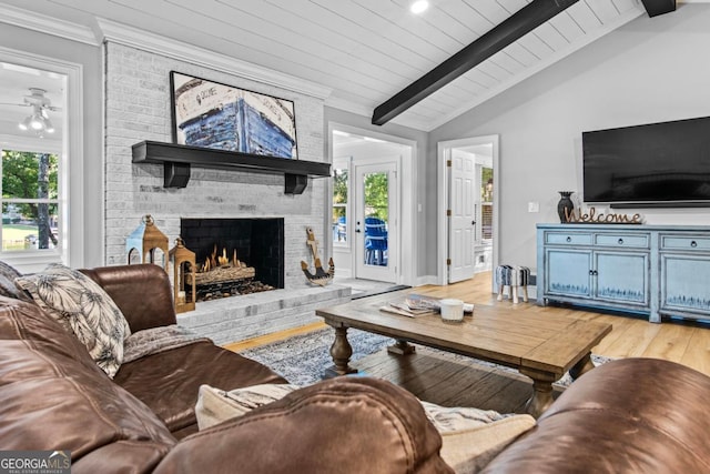 living room with a fireplace, lofted ceiling with beams, light wood-style floors, wooden ceiling, and baseboards