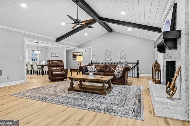 living area with lofted ceiling with beams, a brick fireplace, baseboards, and wood finished floors