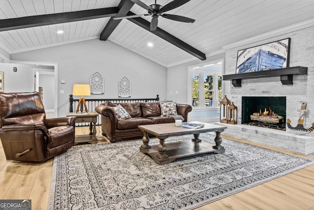 living area with lofted ceiling with beams, a fireplace, wood finished floors, wood ceiling, and a ceiling fan