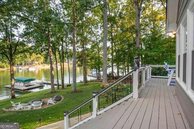 deck with a fire pit, a lawn, a water view, and a floating dock