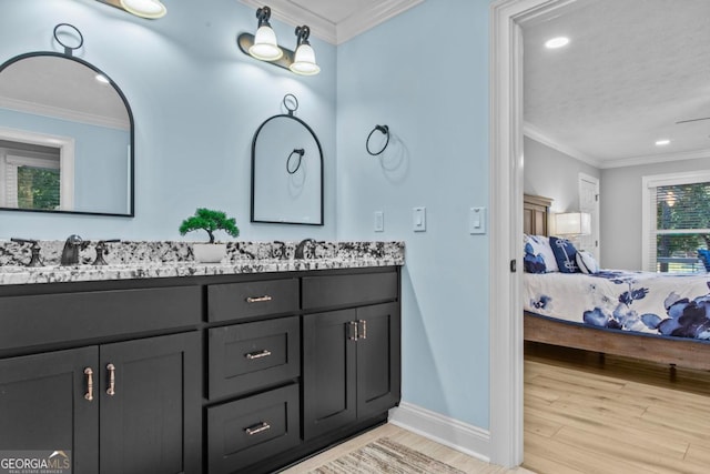 ensuite bathroom with connected bathroom, wood finished floors, a sink, baseboards, and ornamental molding