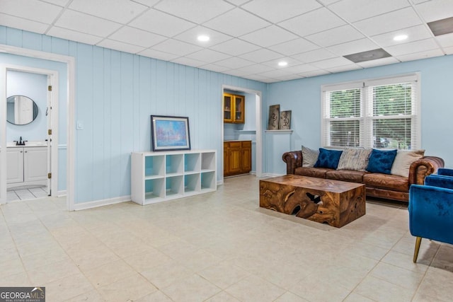 living area featuring a drop ceiling and baseboards