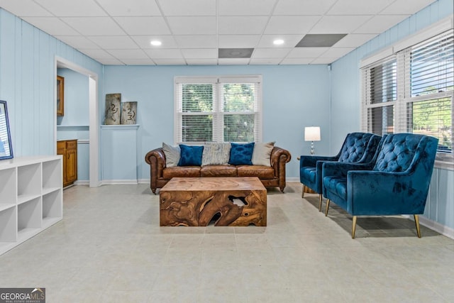 living room with a drop ceiling and baseboards