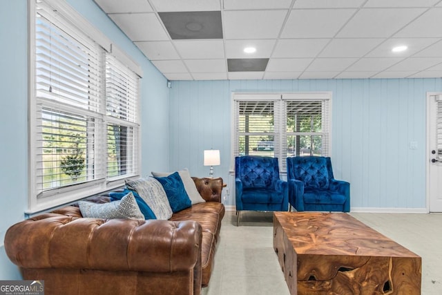 living area featuring a paneled ceiling and baseboards