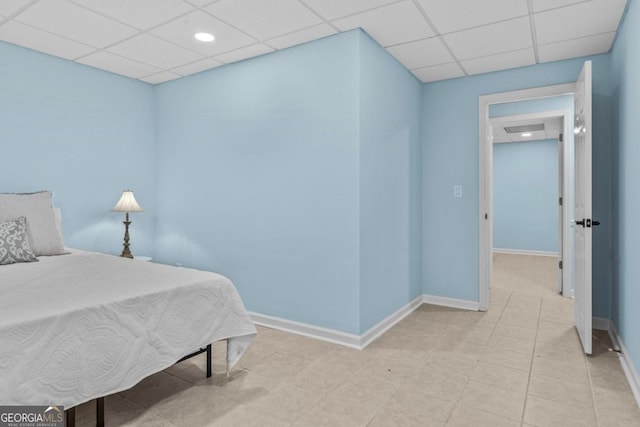 bedroom with a drop ceiling, baseboards, and light tile patterned floors