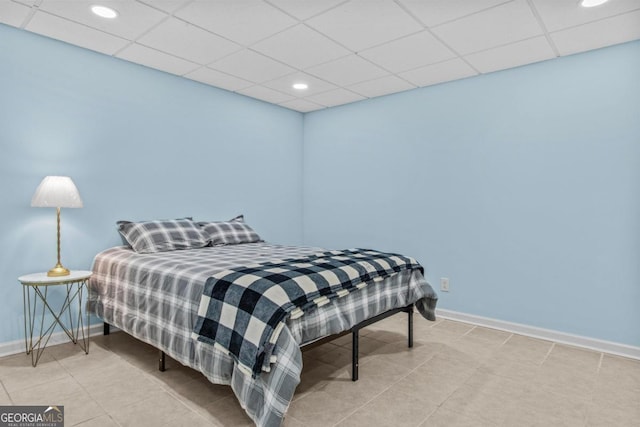 bedroom featuring tile patterned flooring, baseboards, and a drop ceiling