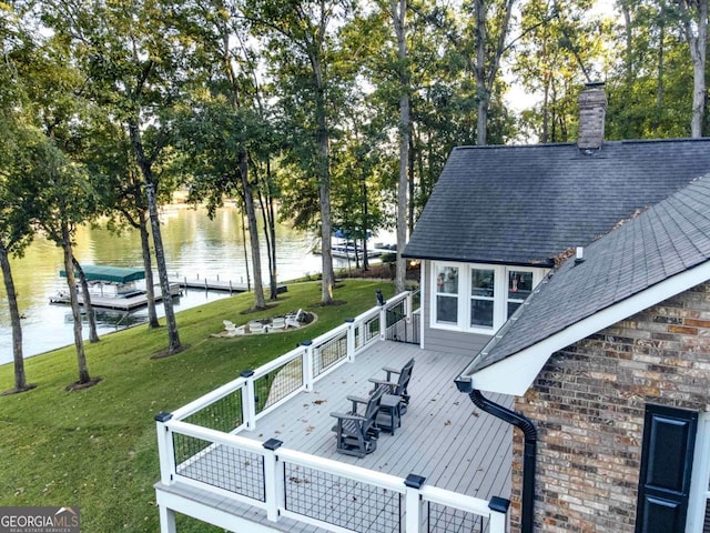 view of home's exterior featuring stone siding, roof with shingles, a dock, a deck with water view, and a yard