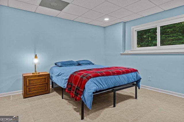 bedroom featuring a drop ceiling, tile patterned flooring, and baseboards