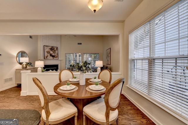 dining space featuring baseboards, a fireplace, visible vents, and wood finished floors