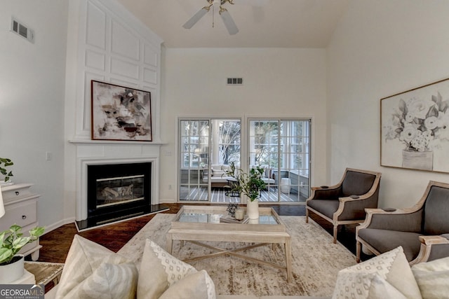 living room featuring a ceiling fan, visible vents, a fireplace, and wood finished floors