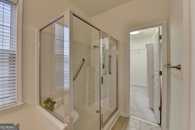 bathroom featuring a stall shower, tile patterned flooring, and a spacious closet