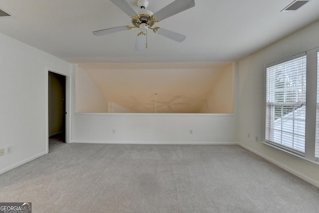 carpeted spare room with a ceiling fan, visible vents, vaulted ceiling, and baseboards