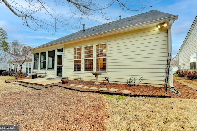 rear view of property featuring roof with shingles and a sunroom