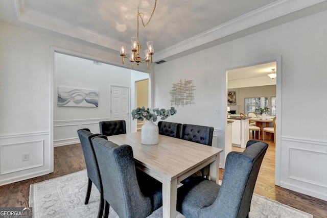 dining area featuring a tray ceiling, wood finished floors, and visible vents