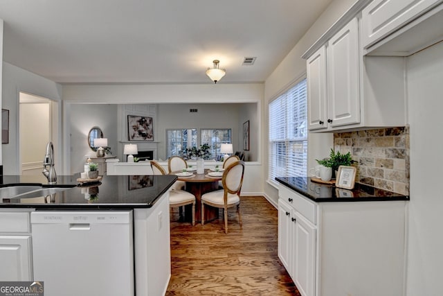 kitchen featuring a fireplace, a sink, visible vents, dishwasher, and dark countertops